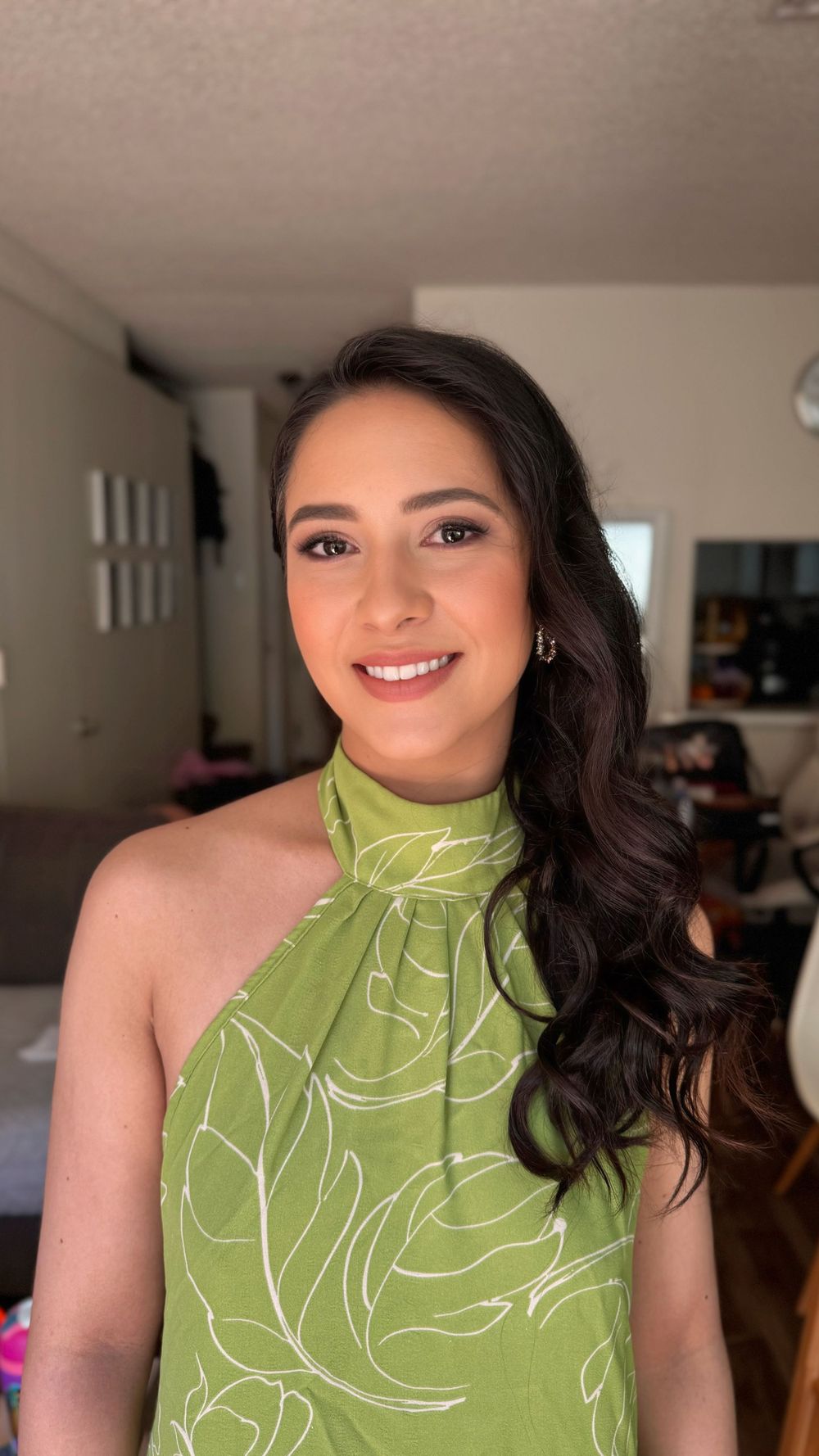 A woman wearing a lime green halter top with white floral pattern smiles while posing for a portrait.