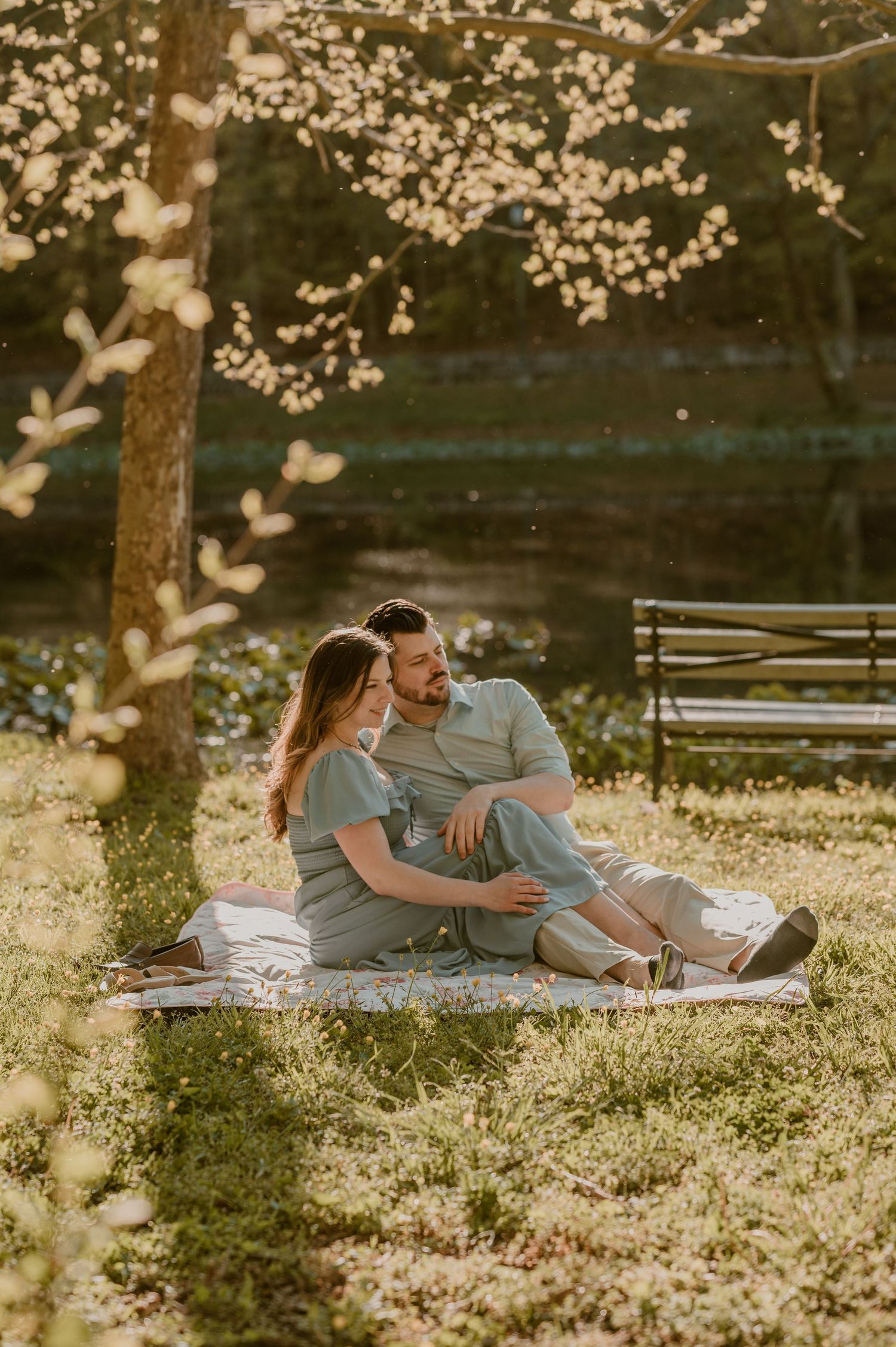 A couple embraces on a brick path during sunset with cherry blossoms blooming in the garden background. photo by Samantha Campbell imagery