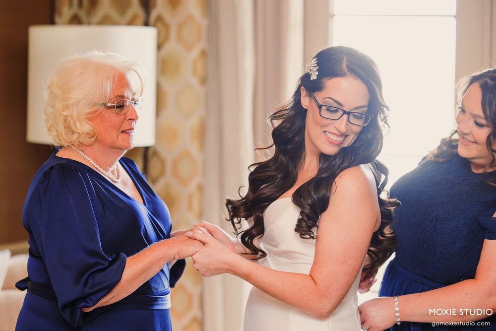 Wedding party members in navy blue attire share emotional embraces during pre-ceremony moments.
