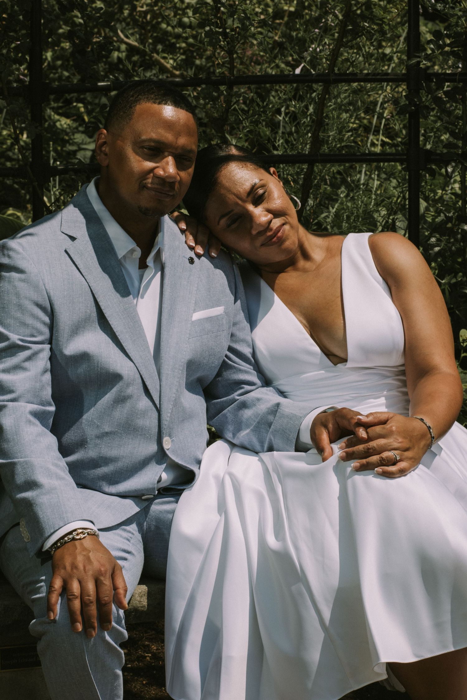 A photo of the bride and groom sitting together, smiling, with the bride resting her head on the groom's shoulder,  a romantic moment