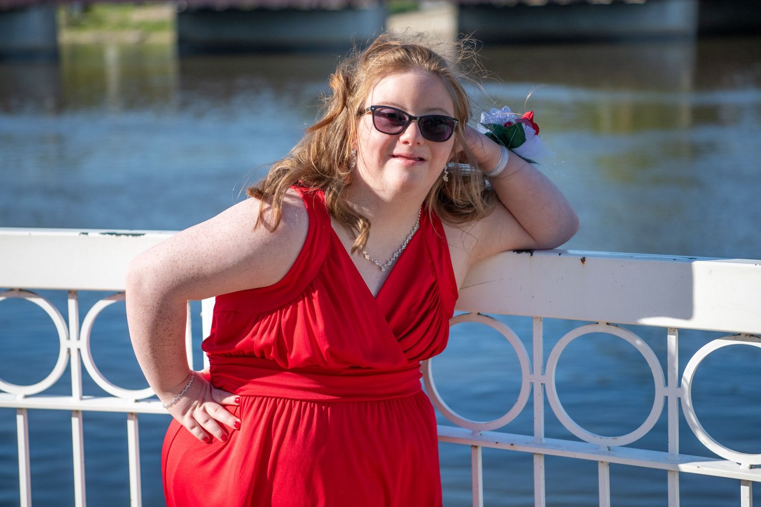Elegant PROM portraits taken at a waterfront location with ornate white railings and blooming trees in the background.