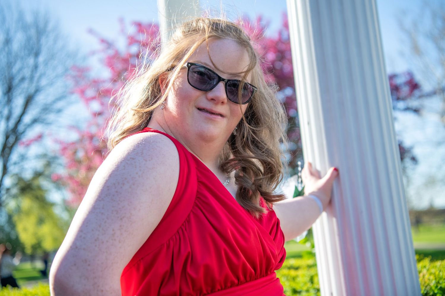 A scenic PROM outdoor photoshoot by a lakeside gazebo with spring flowers in bloom and white railings.