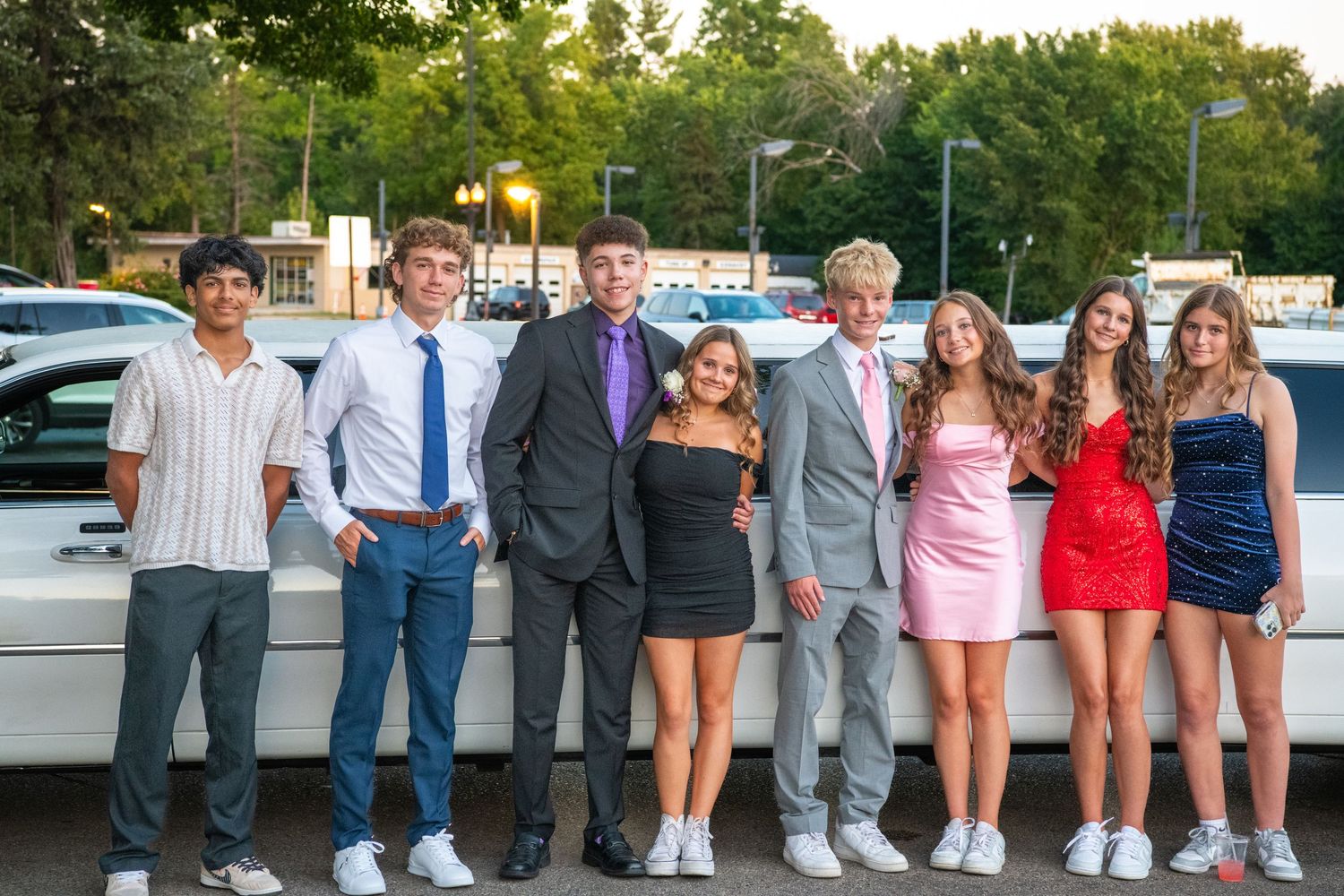 Group photo of wedding party members lined up against a wall outdoors.