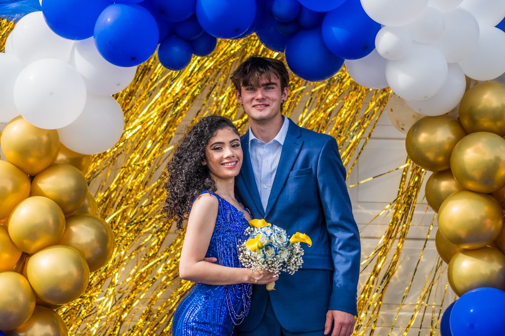 Elegant party setting with balloon decorations and gold tinsel backdrop for formal photos.