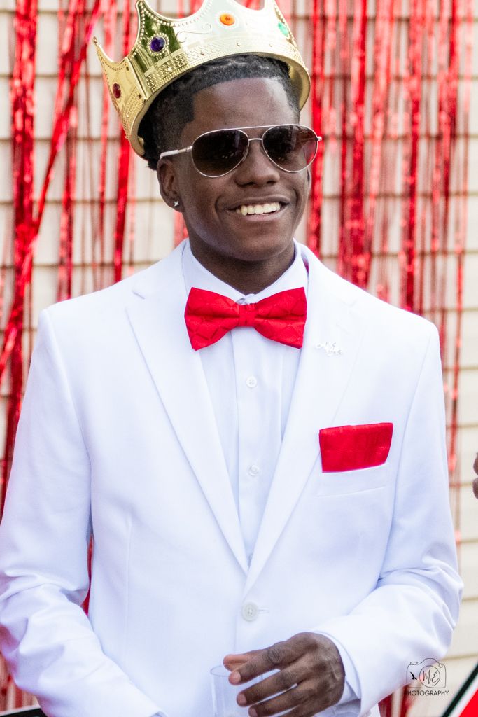 Formal portraits in white suits and red bow ties against red streamer backdrop.