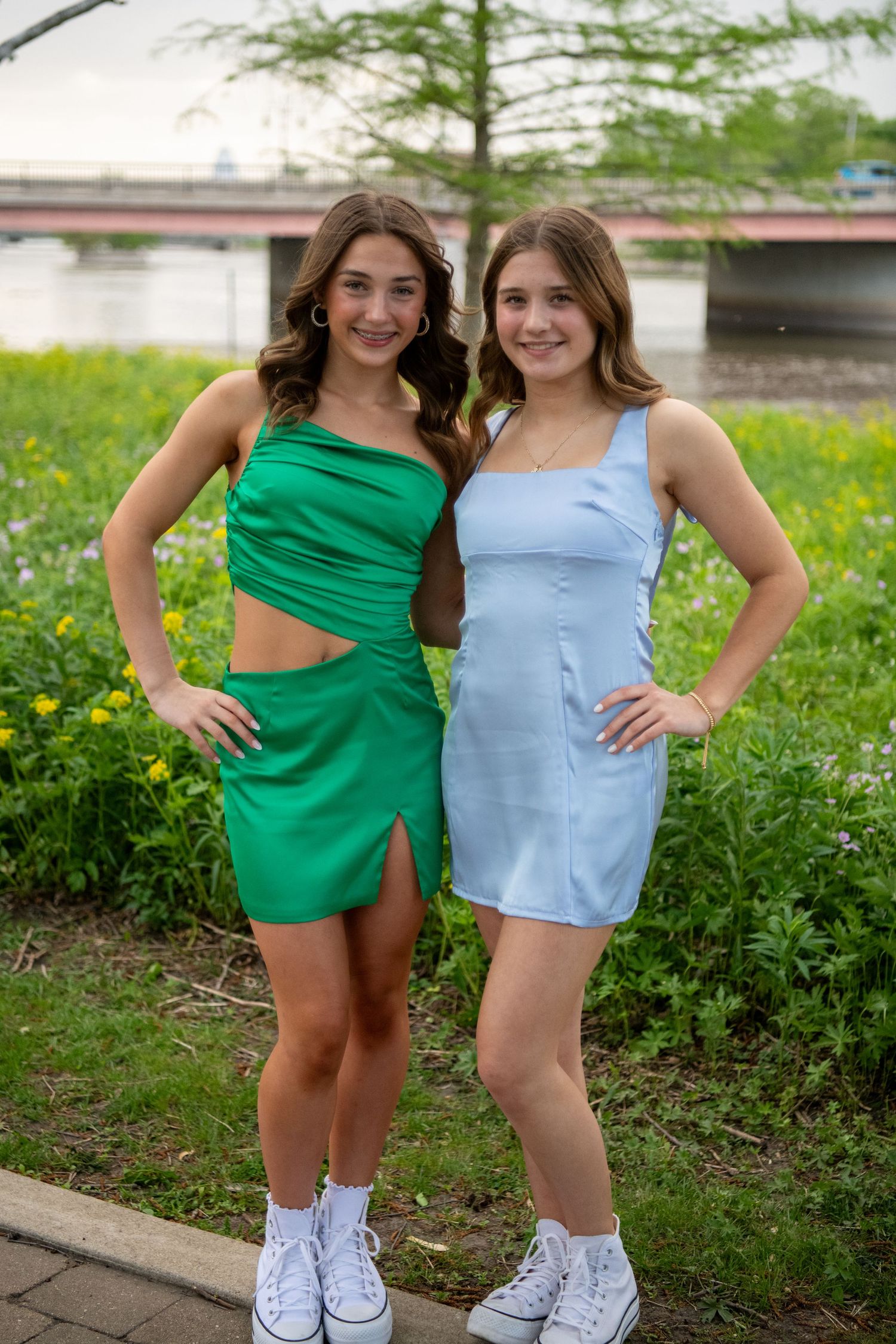 Friends in coordinating blue and green rompers pose together in a park setting.