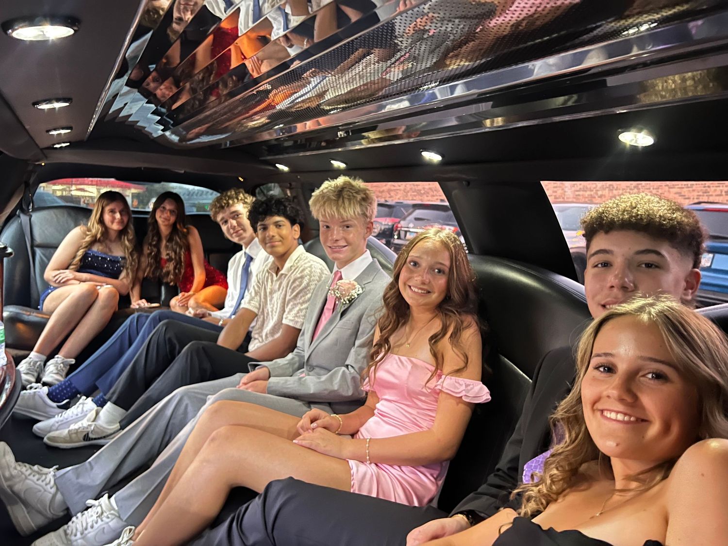 People riding together in a limousine interior with dark lighting and leather seats.