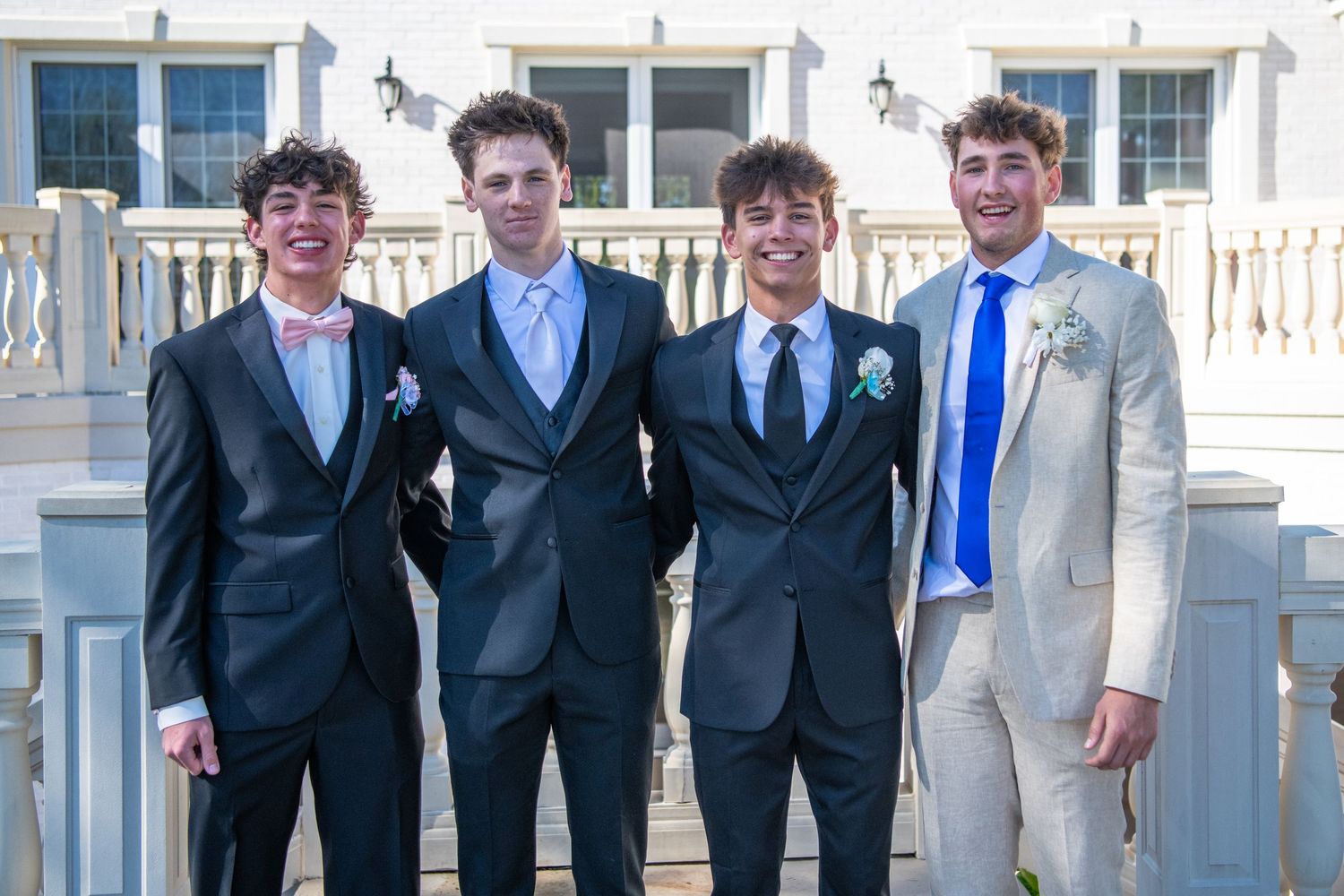 Group of formally dressed people standing together for photo on outdoor terrace.