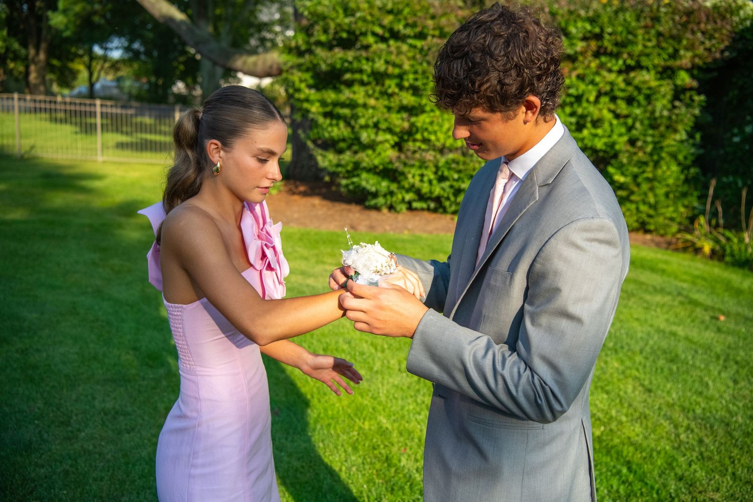 A couple shares a tender moment exchanging rings during an outdoor garden wedding ceremony.