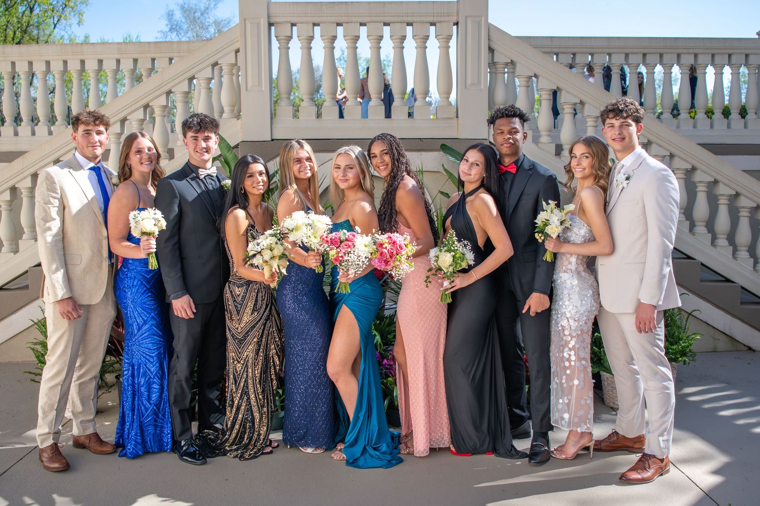 Large formal group photo of event attendees posing on white balcony with decorative railings.