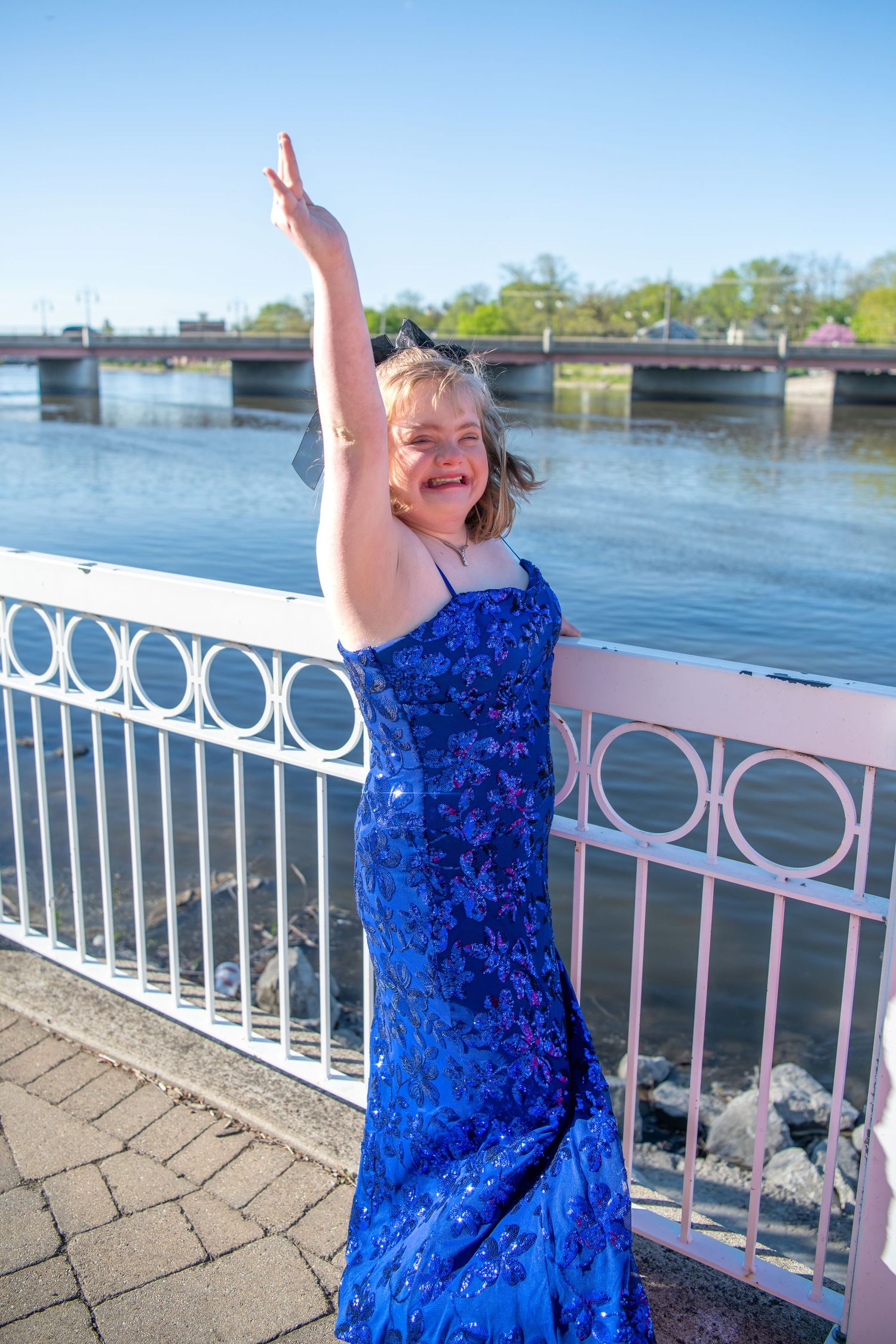 Joyful PROM poses along a waterfront walkway on a sunny day.