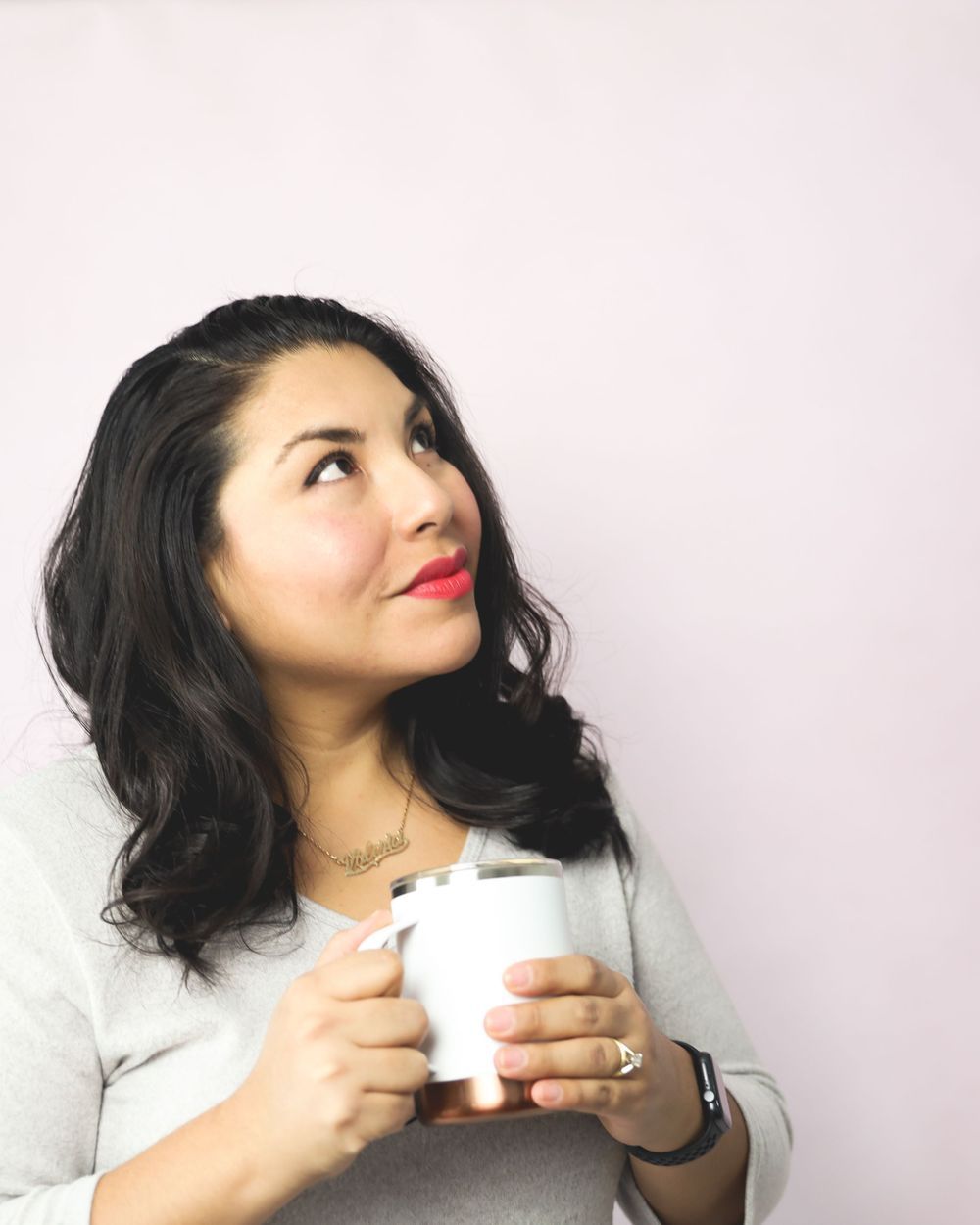 Portrait of someone holding a white coffee mug against a light background.