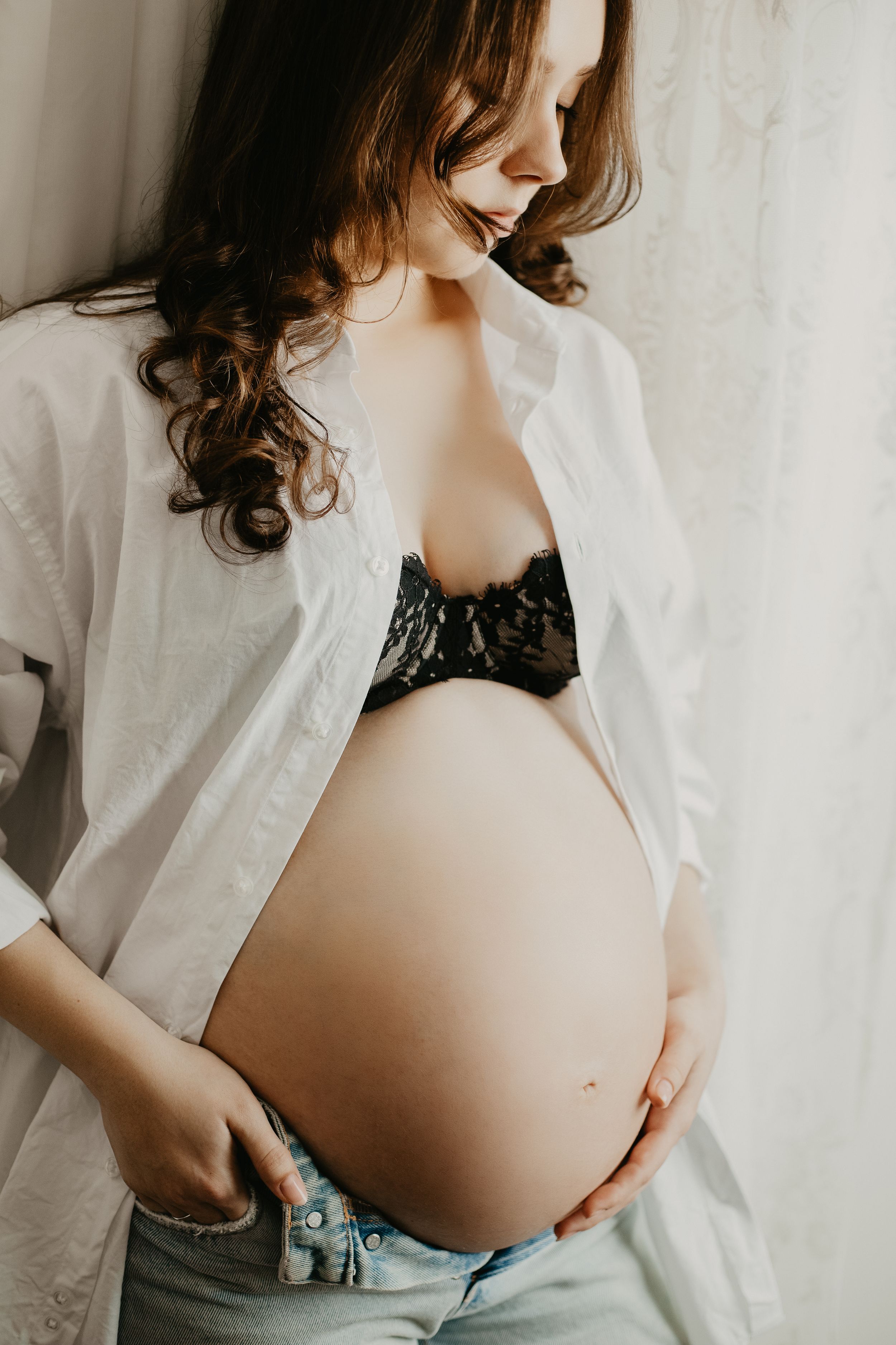 Intimate maternity boudoir photo with white button-down shirt and black lace.
