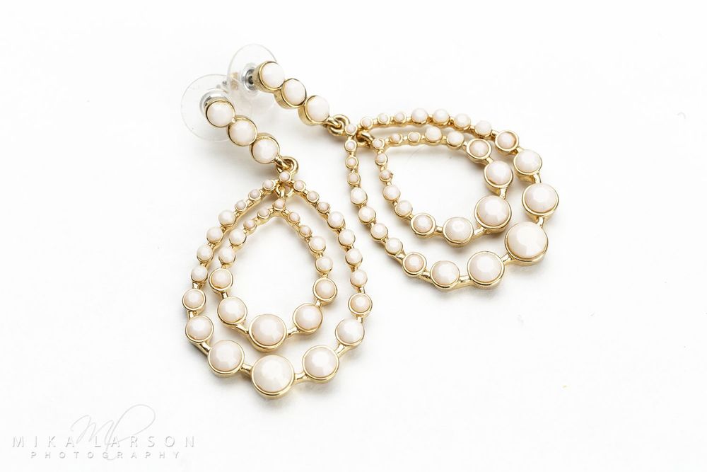 Elegant teardrop-shaped pearl and gold earrings displayed on white background.