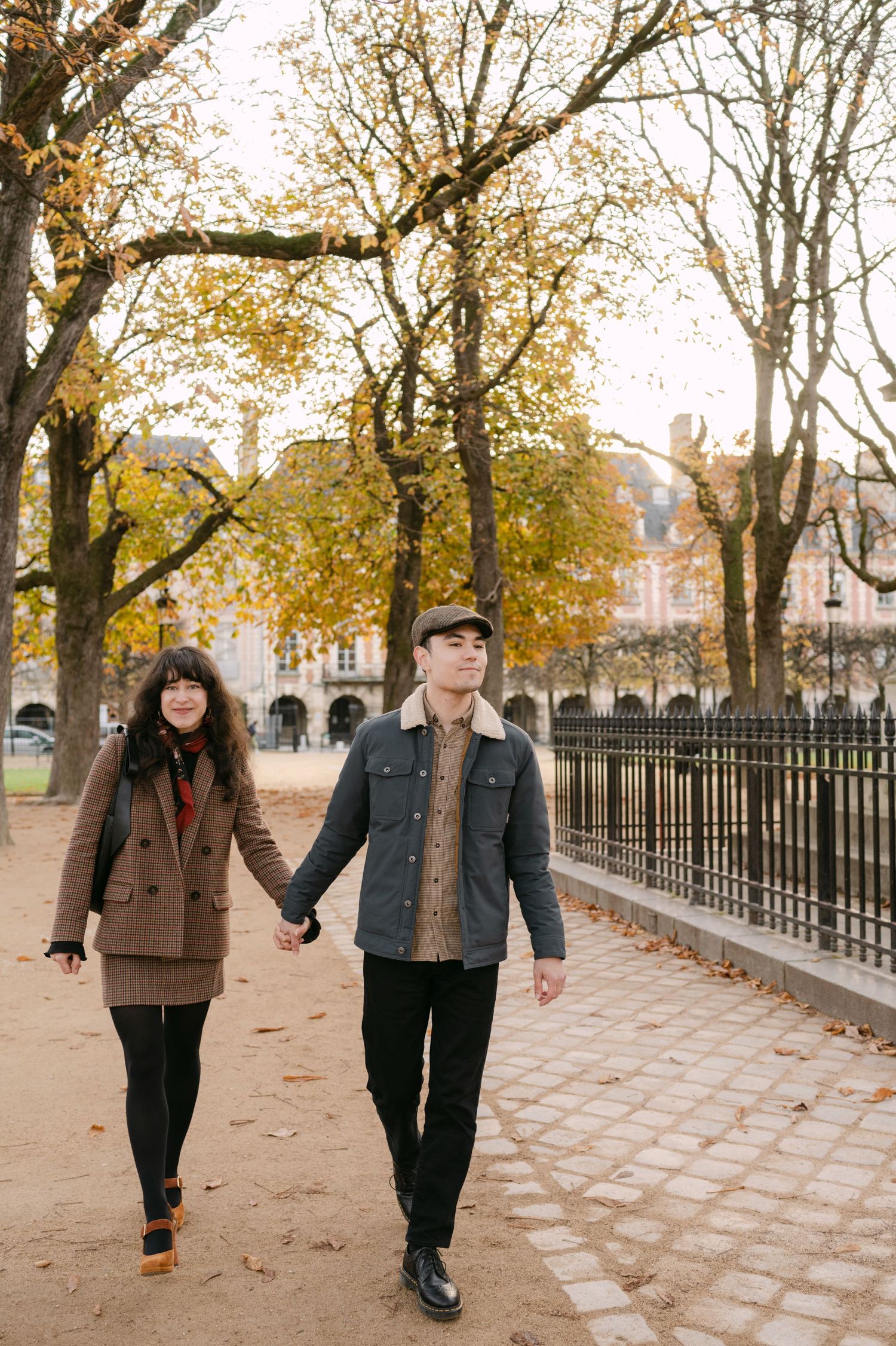 A couple in elegant attire poses at sunset in front of a grand French chateau.