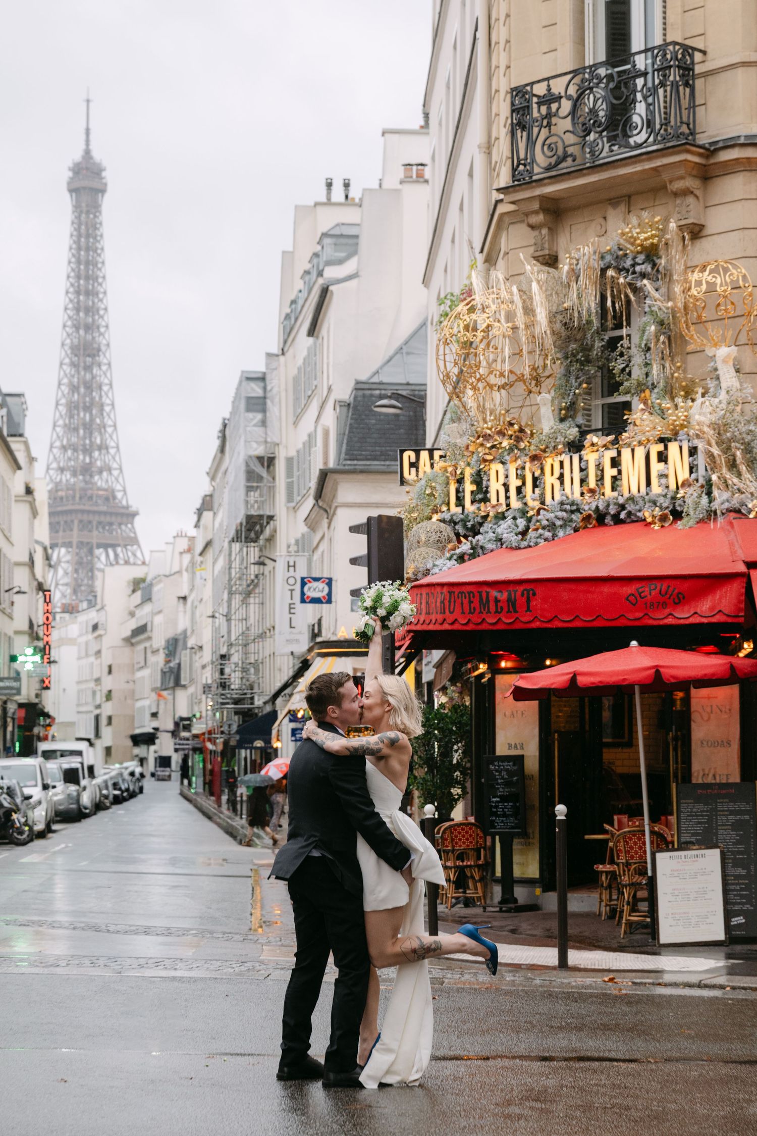 Romantic embrace under rain on Paris street with Eiffel Tower in background.