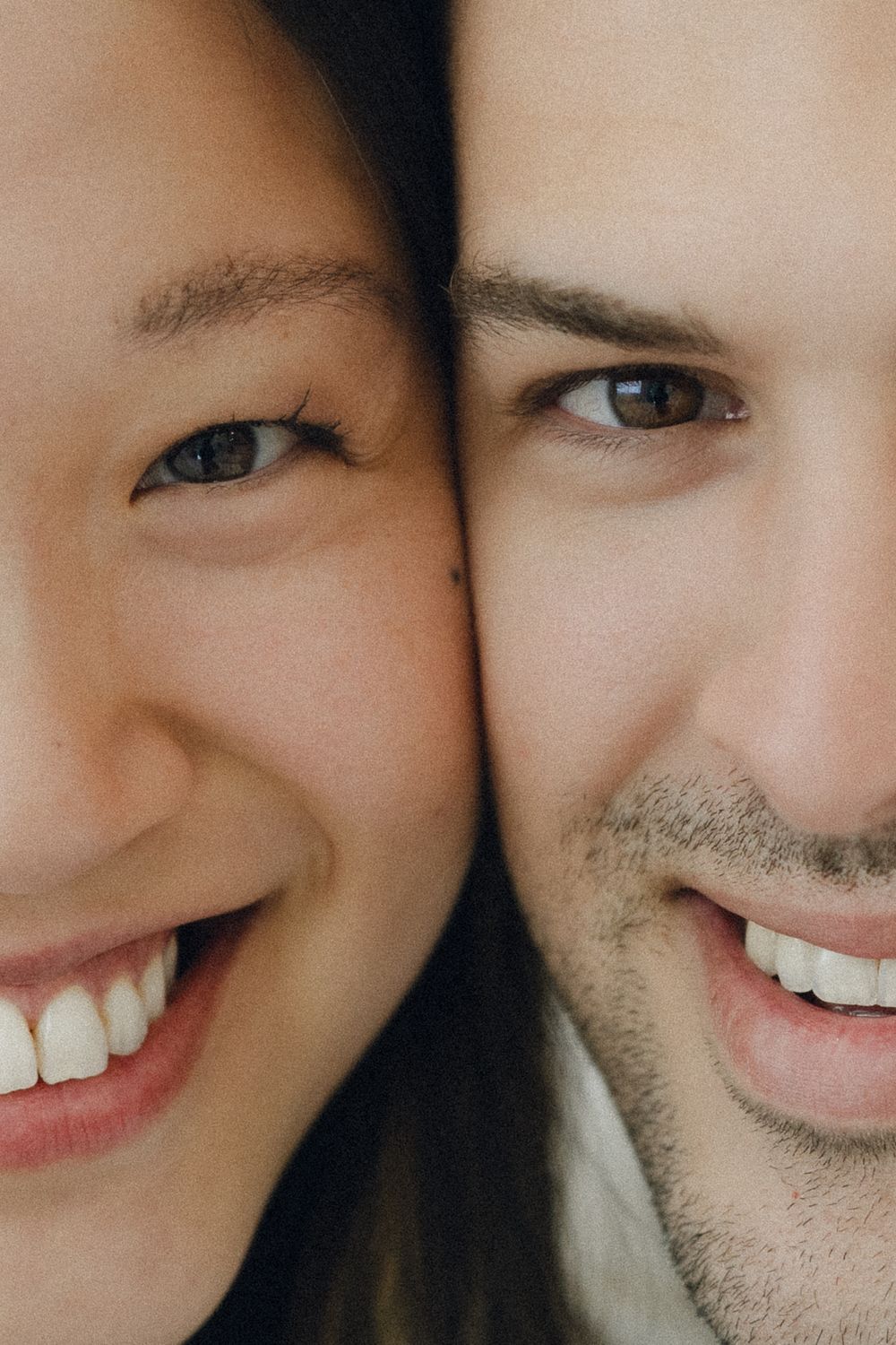 Close up of two people smiling brightly while leaning close together in intimate portrait.