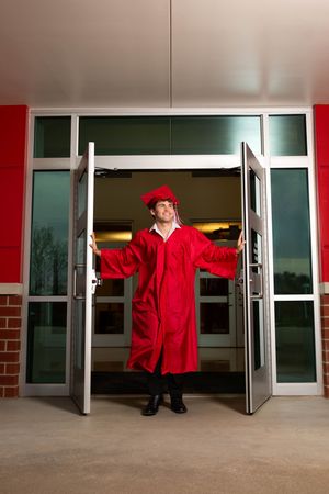 Graduate in red cap and gown stands triumphantly in open school doors, symbolizing academic achievement.