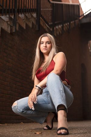 Senior girl pose from low angle while leg stretched toward camera