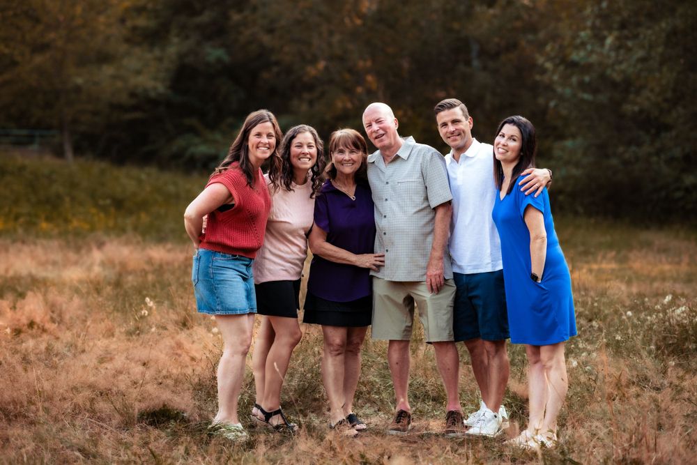 A group poses together casually outdoors in a grassy field during golden hour.