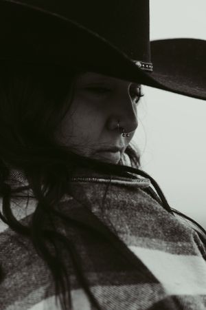 Moody black and white profile silhouette of someone wearing a cowboy hat and flannel
