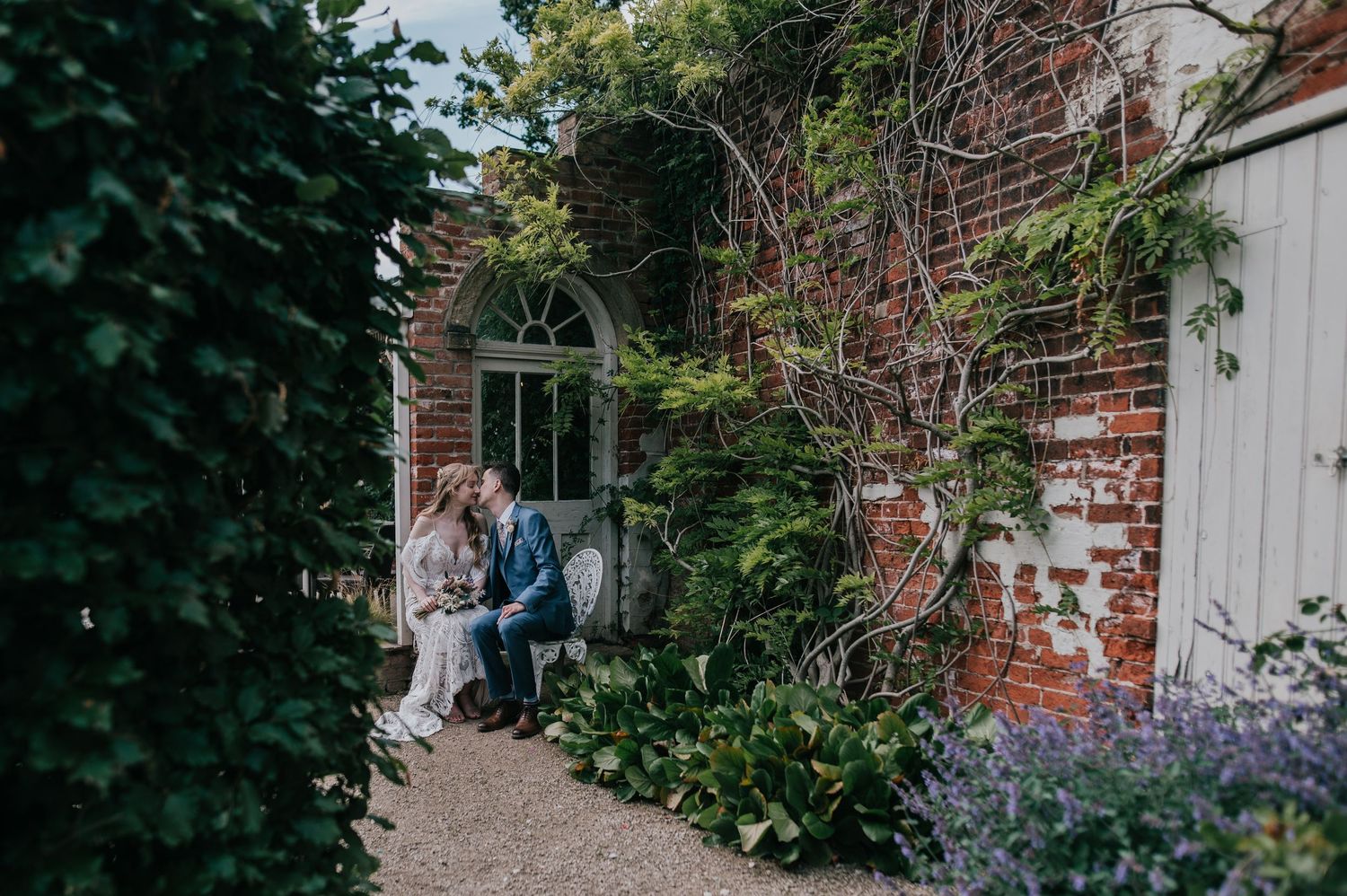 Wedding ceremony in brick-walled venue with floral arch decorations.