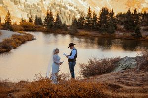 Panoramic view of a lakeside landscape with evergreen trees and golden sunset light reflecting on the water.