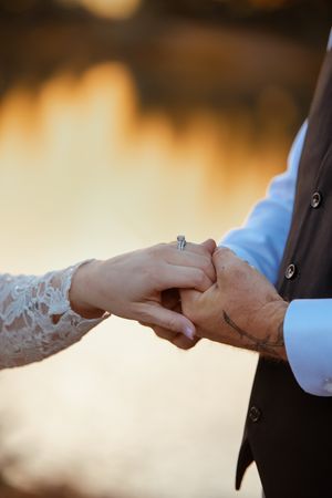 Close-up sequence of hands exchanging wedding rings during a romantic sunset ceremony.
