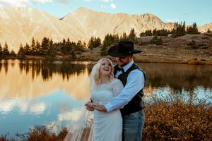 Wedding portraits captured at a serene alpine lake with snow-capped peaks in the background.