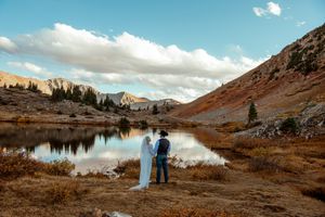 Panoramic mountain landscape with rocky peaks and alpine lake reflecting clouds in the Medicine Bow Mountains of Wyoming.
