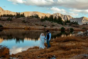Scenic mountain vista with calm lake waters reflecting rugged peaks and autumn colors in Medicine Bow National Forest.