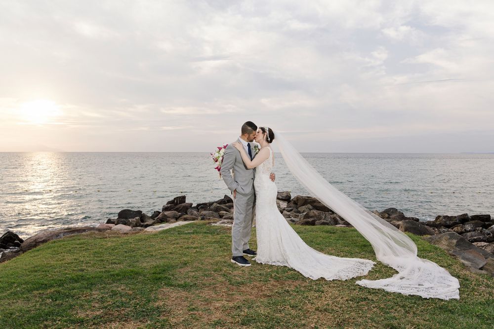 Una romántica ceremonia de boda junto a la playa al atardecer, con un vestido blanco vaporoso que se refleja en la brisa del mar.