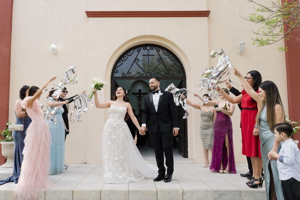 Wedding party lineup against a beige wall creating fun poses for photos.