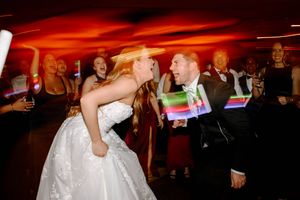 Bride and groom dancing joyfully with glowing light sticks at their wedding reception party.
