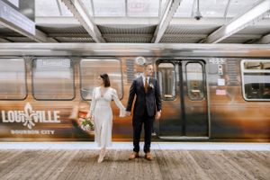 Modern wedding portrait of a couple holding hands on a train platform, captured by a wedding photographer