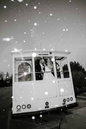 Black and white photo of a bride and groom celebrating on a vintage trolley with sparkling bokeh effects.