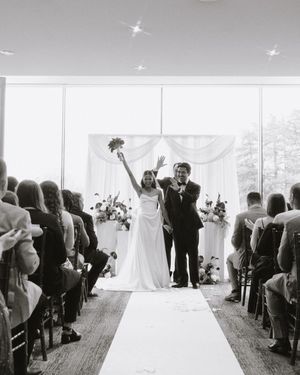 Black and white photo of a joyful bride and groom walking down the aisle after their wedding ceremony.