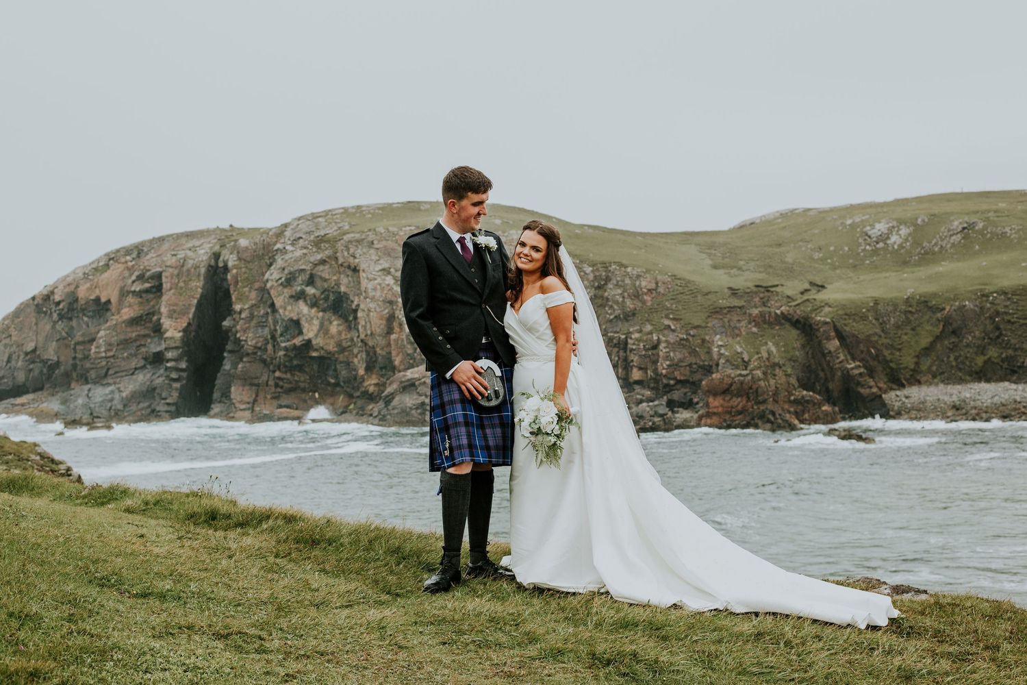 Couple in wedding attire holding hands on pristine beach with turquoise water.