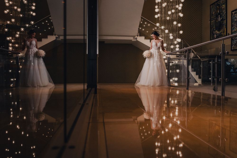 A dreamy wedding scene with a reflection in dark glass showing a person in a white dress against twinkling lights.