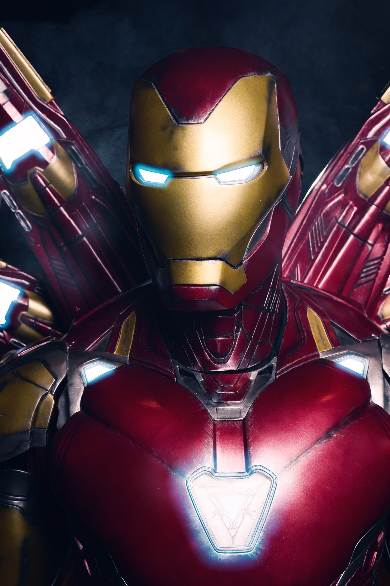 Iron Man armor with glowing arc reactor and lit-up eyes in a dark atmospheric portrait shows metallic red and gold details.