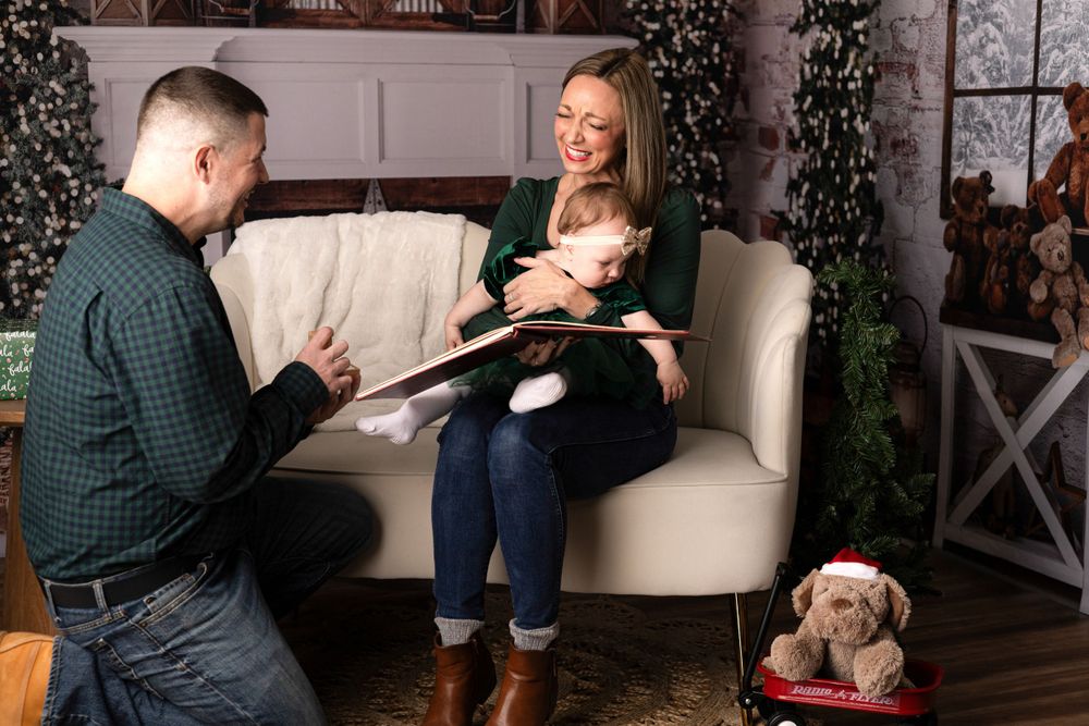 Family photo session with Christmas decorations and cozy white couch in studio setting.