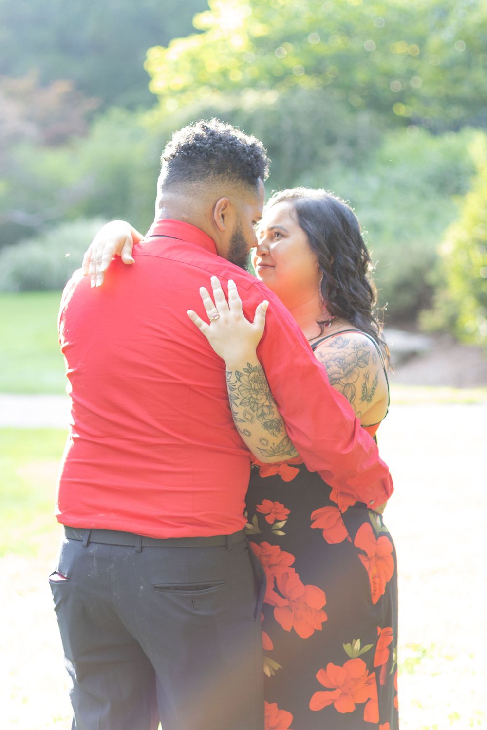 Wedding couple in red and black attire sharing intimate moments in a garden setting.