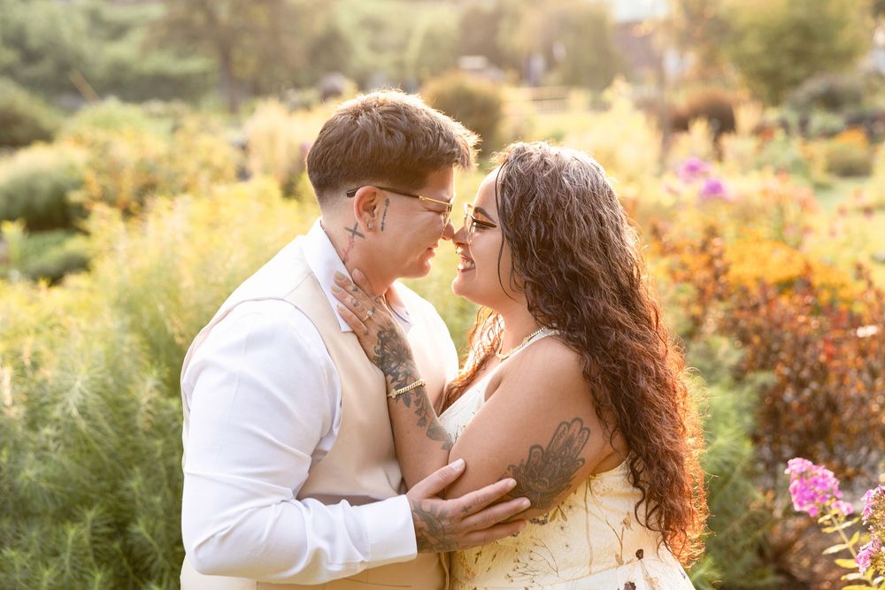 Romantic couple embraces in a sunlit garden filled with colorful flowers during golden hour.