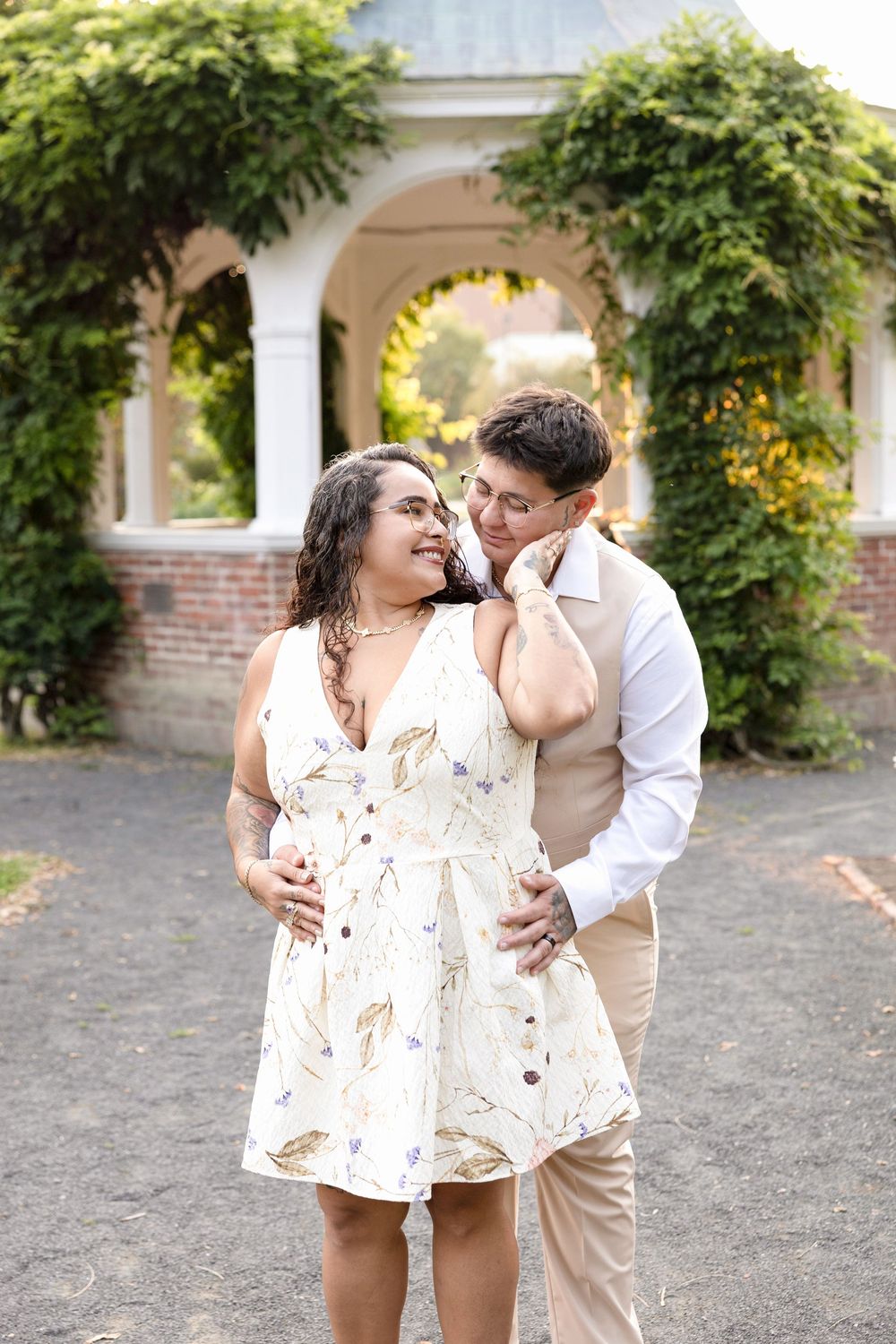 Romantic couple photos in white and beige outfits near garden pillars.
