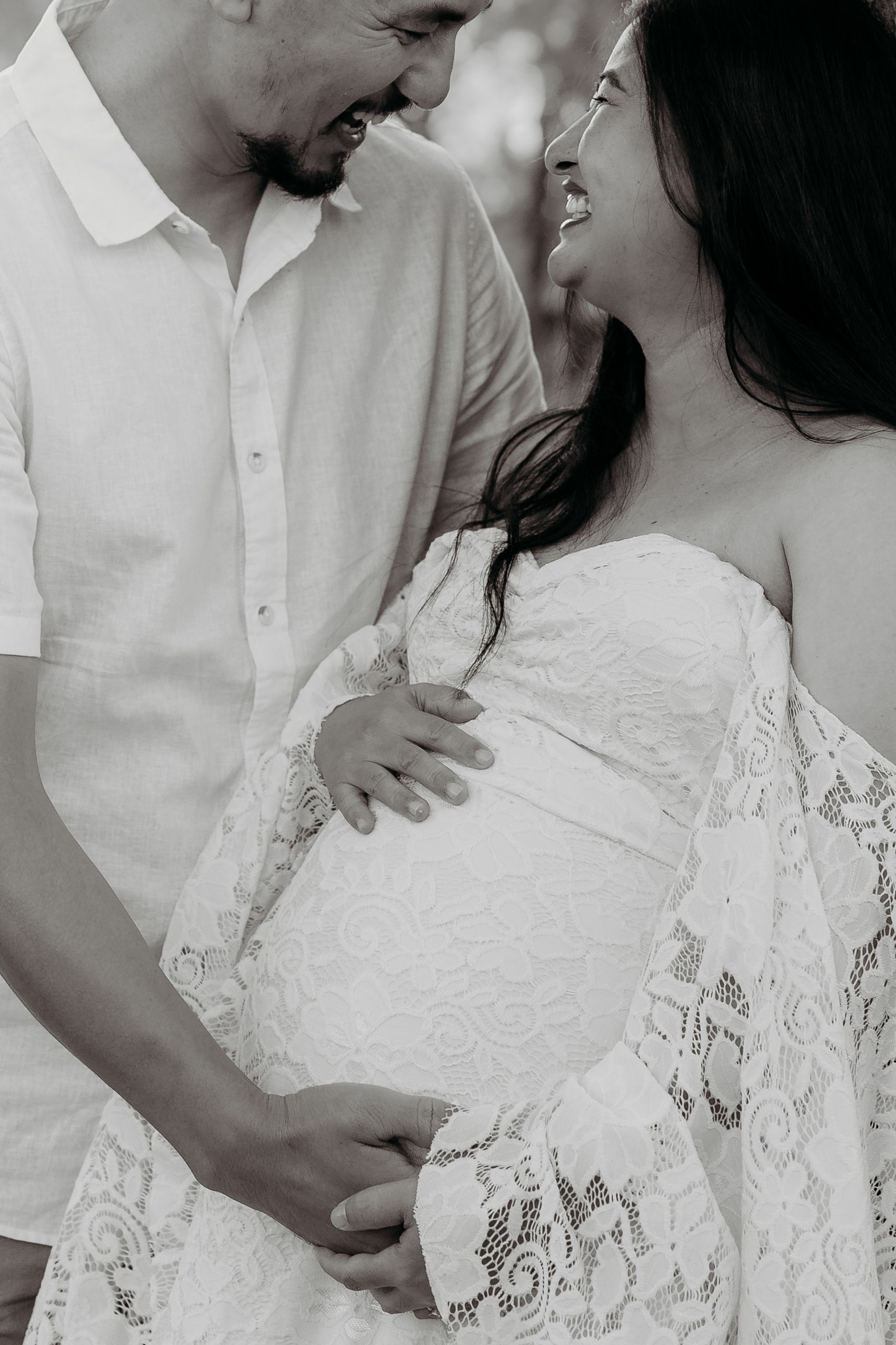 Black and white photo of couple tenderly cradling pregnant belly together outdoors. Bathurst maternity photography.