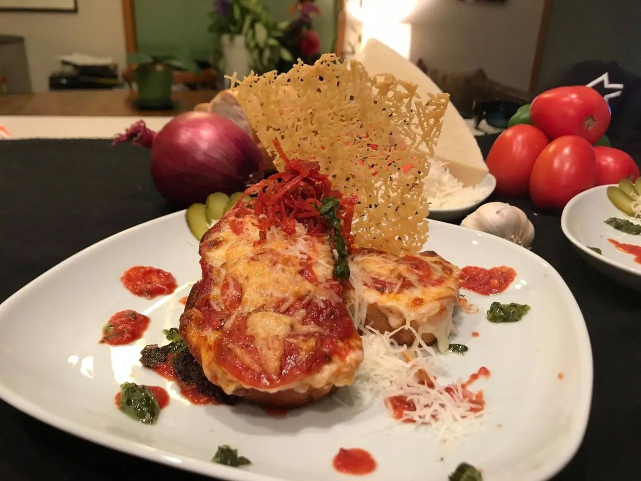Gourmet plated dish with red sauce, crispy garnish and fresh tomatoes on white plate.