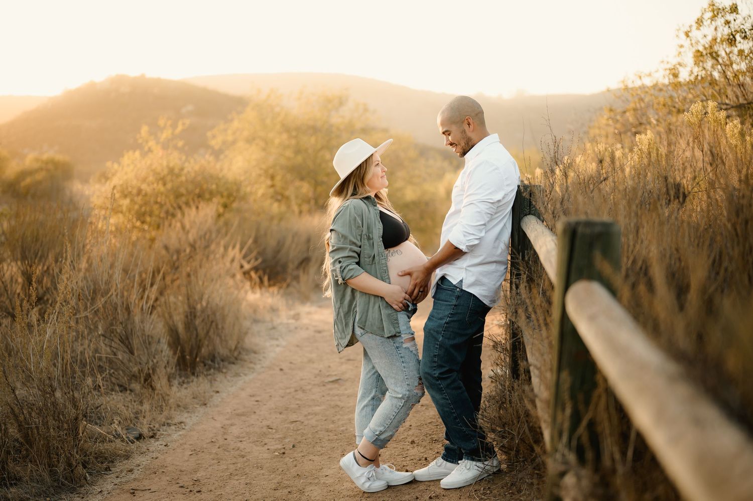Couple standing in grassy mountain field during their maternity photoshoot in Ojai by Ventura maternity photographer