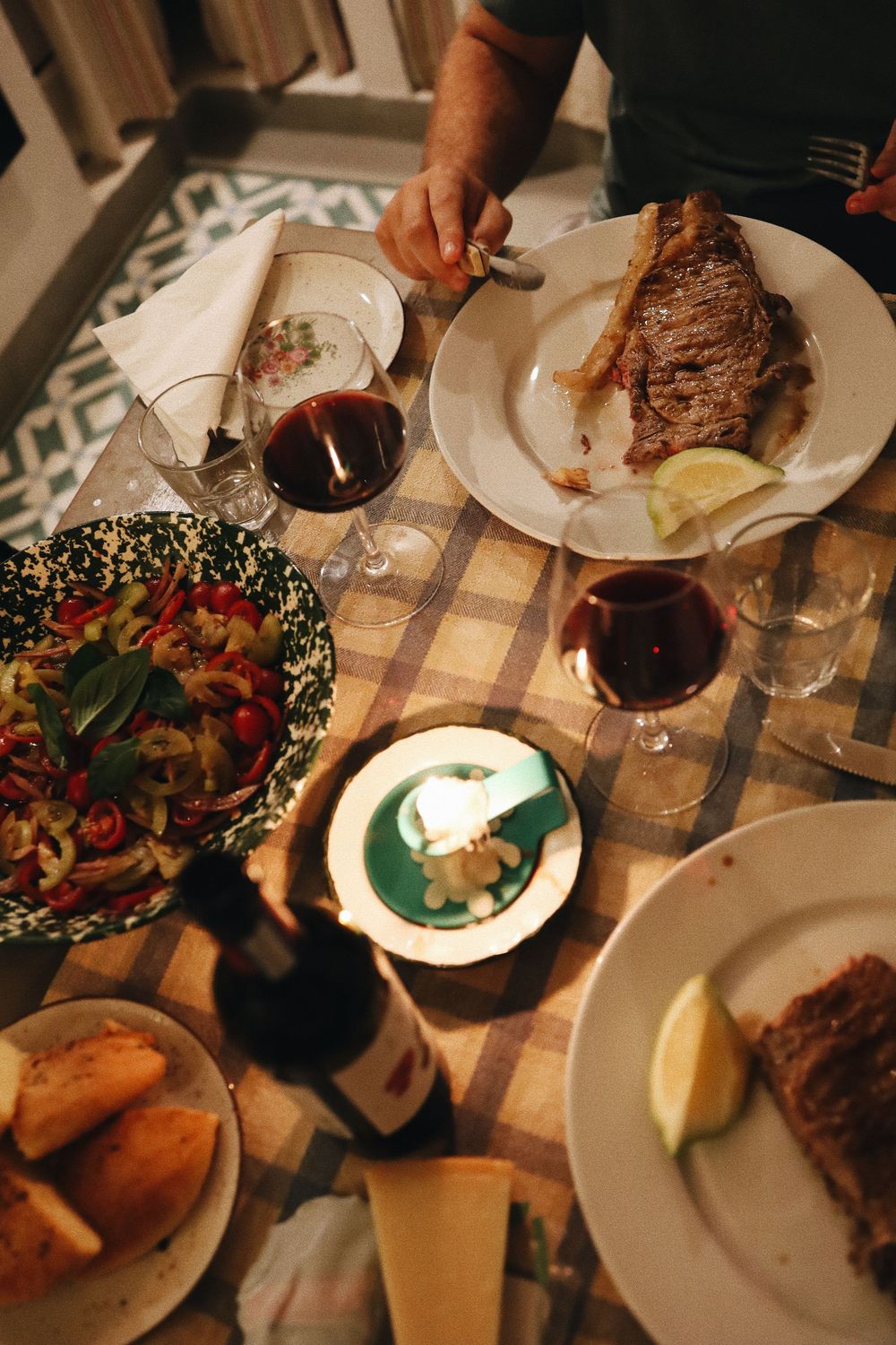 Overhead view of dinner plates on a table with wine glasses and multiple dishes during an elegant dining experience.