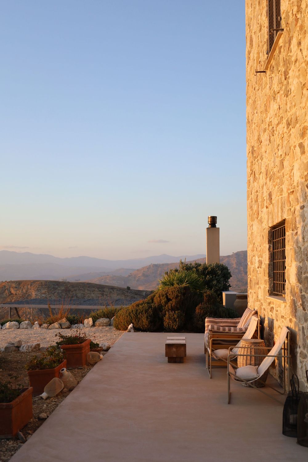 Mediterranean villa terrace with stunning panoramic mountain views and rustic stone columns at sunset.