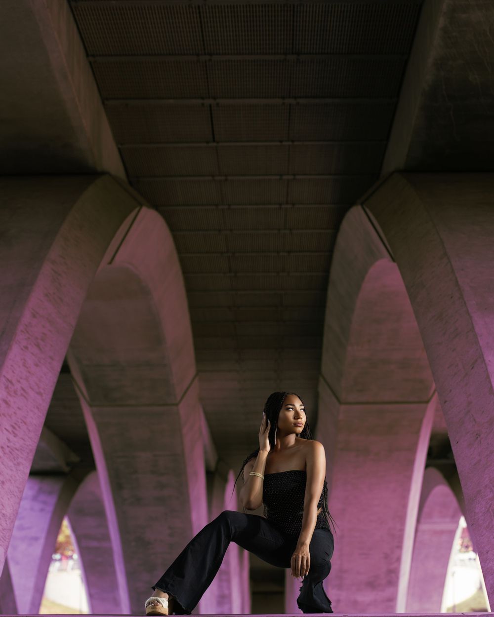 Senior under illuminated concrete arches with purple lighting creating dramatic architectural shadows. Kentucky senior photographer